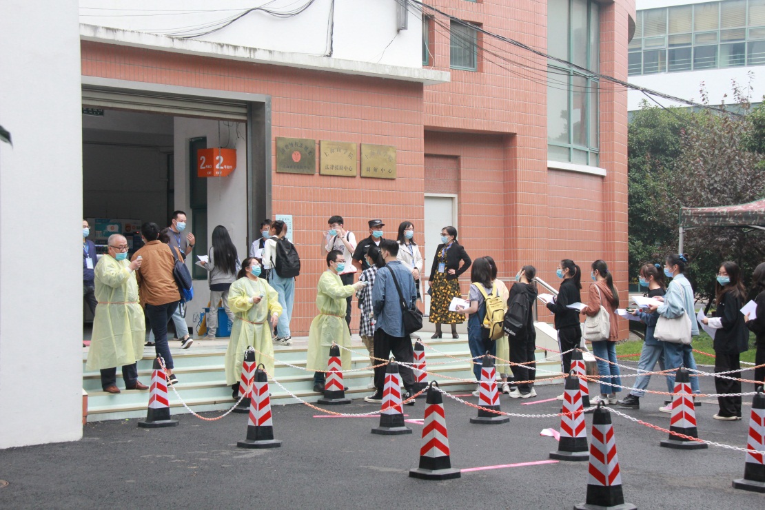 图为考生进入考场前，工作人员做好体温测量工作