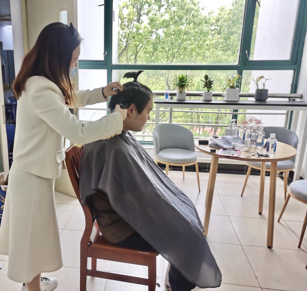 图为林孜老师为同学们理发
