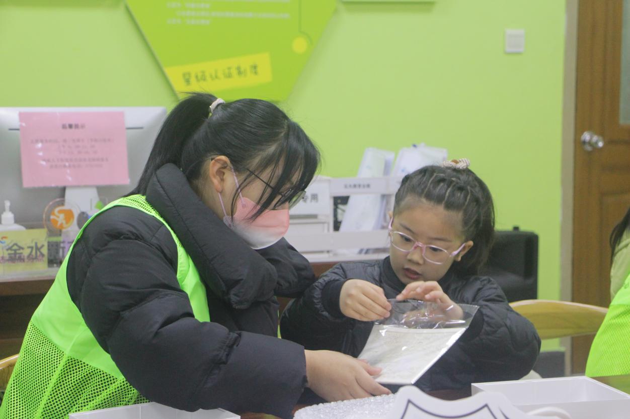 图为志愿者帮助小朋友制作纸雕